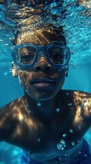 Fototapeta premium A young boy with swimming goggles explores underwater, surrounded by shimmering bubbles and light reflections from the surface. He enjoys the refreshing experience