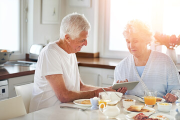 Senior couple, tablet and eating food in kitchen on social media, reading blog and internet search....