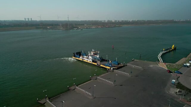Drone footage of a ferry leaving the port in Scheur River heading to Rozenburg on a sunny day