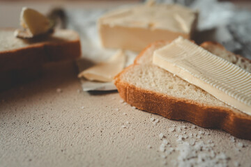 A close-up of a slice of bread with butter on a textured surface, sprinkled with coarse salt. A rustic and simple breakfast or snack setup with soft natural lighting and a warm atmosphere