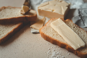 A close-up of a slice of bread with butter on a textured surface, sprinkled with coarse salt. A rustic and simple breakfast or snack setup with soft natural lighting and a warm atmosphere