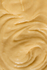 Close-up of smooth, creamy batter with a swirled texture. The golden-yellow mixture reflects light,...