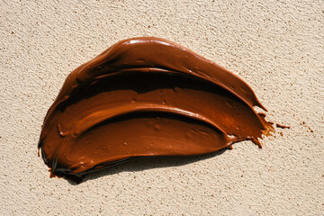 Close-up of smooth chocolate frosting with rich texture and deep brown color. The creamy, glossy surface has distinct swirls, highlighting its velvety consistency, perfect for cakes and desserts