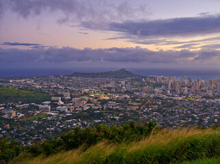 City, landscape and sky at sunset with mountain in Oahu, view and urban background with clouds, land and nature. Sunrise, skyline and environment for travel, vacation and tropical paradise adventure