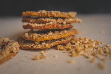 Stack of dried apple slices with crushed nuts on top. Healthy homemade fruit chips with nuts on light background. Natural organic snack, vegetarian food, diet dessert, close-up