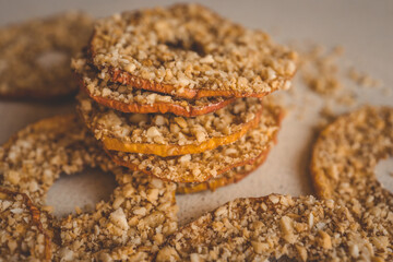 Stack of dried apple slices with crushed nuts on top. Healthy homemade fruit chips with nuts on light background. Natural organic snack, vegetarian food, diet dessert, close-up