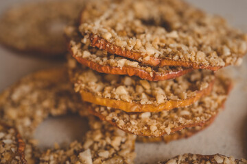 Stack of dried apple slices with crushed nuts on top. Healthy homemade fruit chips with nuts on light background. Natural organic snack, vegetarian food, diet dessert, close-up