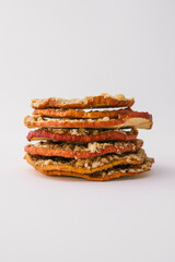 Stack of dried apple chips with chopped nuts on white background. Healthy vegan snack, organic diet food, crispy sweet apple slices, sugar-free dessert for children and adults