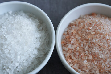 Himalayan salt in two bowls on black background, top view