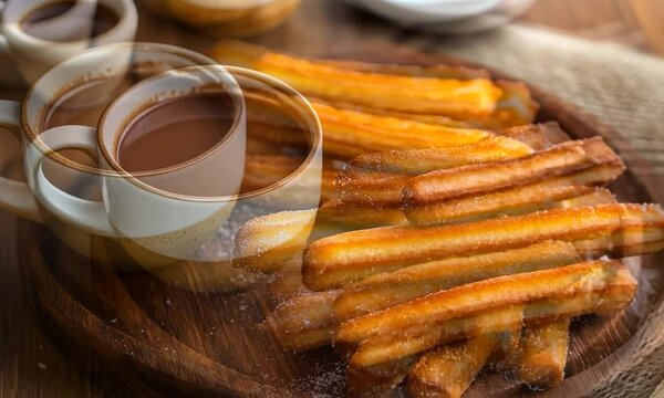 Delicious golden churros served on a wooden platter with a cup of rich chocolate sauce nearby