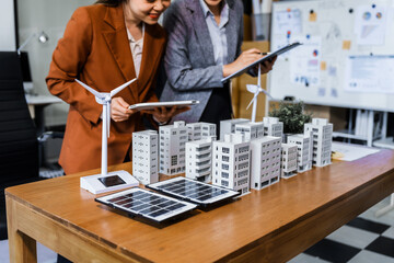 Two businesswomen sit at a desk in a meeting, discussing property development while building a...
