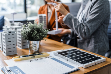 Two businesswomen sit at a desk in a meeting, discussing property development while building a...