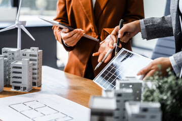 Two businesswomen sit at a desk in a meeting, discussing property development while building a...