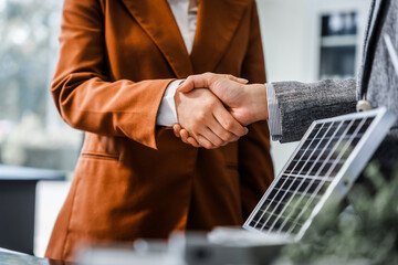Two businesswomen shake hands at desk, finalizing deal on property development. real estate...