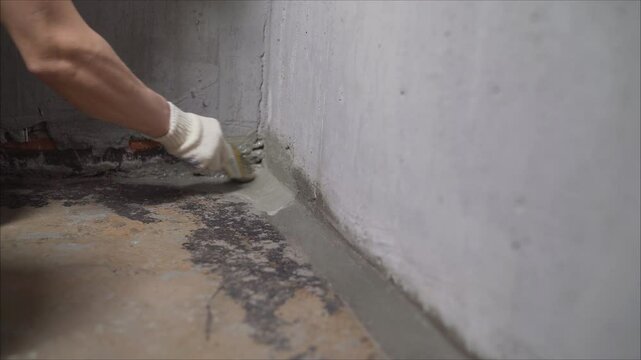 Construction worker applying cement to floor and wall joint