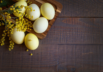 Decorative Easter egg and mimosa wreath on wooden background. Top view, space for text.