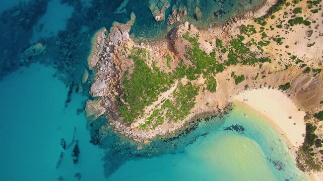 An aerial shot capturing the rugged beauty of El Gliaa's coastline in Bizerte, Tunisia. The clear turquoise waters contrast beautifully with the rocky shore and green vegetation.
