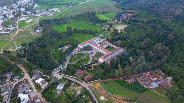 This stunning aerial shot captures the historical complex in Thibar, Beja, surrounded by lush greenery and well-maintained gardens. The intricate layout and architectural beauty.