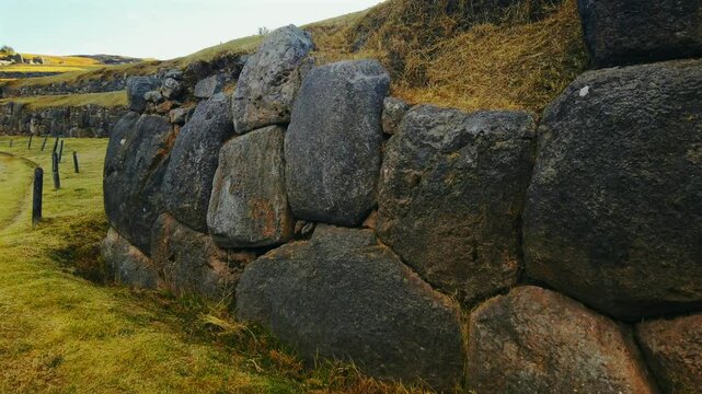 Close up view showcasing massive megalithic stone walls of Sacsayhuam&aacute;n. Pan left reveals the terraced ruins of the ancient inca complex outside Cusco, Peru