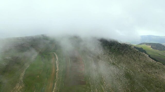 An aerial perspective of the foggy terrain in Djebba, Beja. The mist partially obscures the rocky landscape, creating a dramatic and ethereal atmosphere.