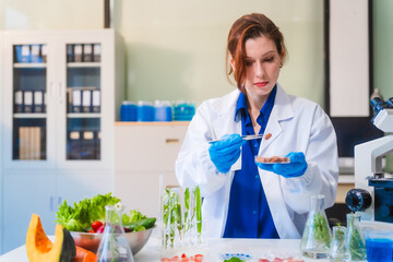 Middle-aged female laboratory worker wearing blue gloves conducts lab test on food ingredients...