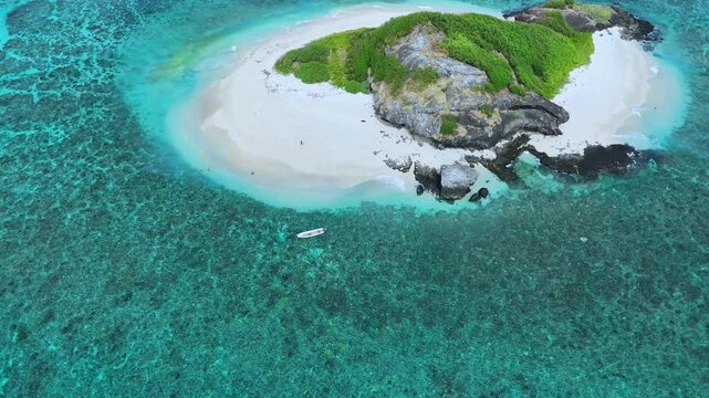 Aerial drone footage captures Fiji&rsquo;s Island, shaped like a dodo bird, surrounded by turquoise waters. The video showcases white beaches, monumental coral reefs, and lush tropical landscapes.