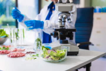 Middle-aged female laboratory worker wearing blue gloves conducts lab test on food ingredients...