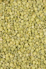 A close-up, top-down view of a pile of dried green split peas filling the frame