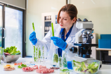 Middle-aged female laboratory worker wearing blue gloves conducts lab test on food ingredients...