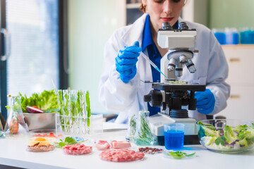 Middle-aged female laboratory worker wearing blue gloves conducts lab test on food ingredients...