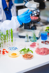 Middle-aged female laboratory worker wearing blue gloves conducts lab test on food ingredients...