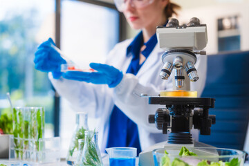 Middle-aged female laboratory worker wearing blue gloves conducts lab test on food ingredients...
