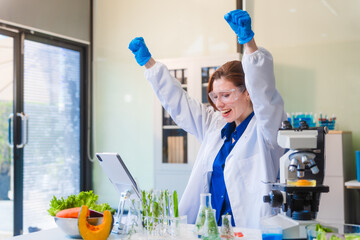 Middle-aged female laboratory worker wearing blue gloves conducts lab test on food ingredients...