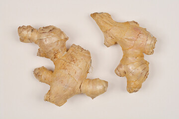 A top-down shot of two ginger roots on a light-colored surface, showcasing their irregular shapes and beige tones