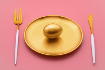 golden egg on golden plate a glistens alongside luxurious cutlery against a vibrant pink...