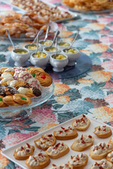 Breakfast table with Galician desserts and appetizers, tea pastries, carnival ears, small cups of fresh fruit, colorful tablecloth, hydrangeas