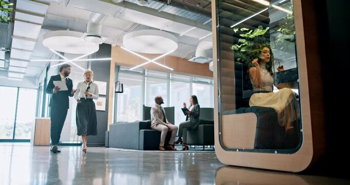 Collaboration, conversation and walking with business people in lobby of office for planning. Discussion, documents and teamwork with employee on video call in pod for development, feedback or review