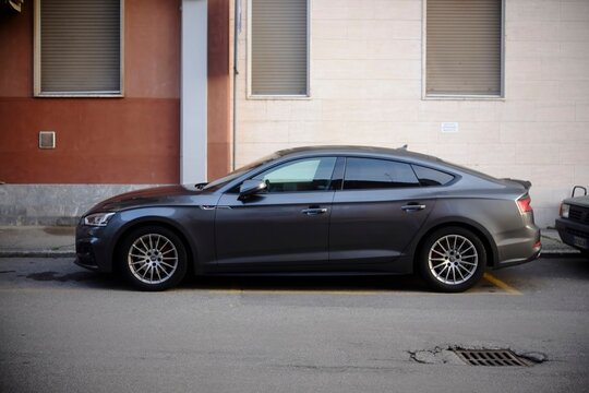 Gray Audi S5 Sportback parked on Cremona street, tinted windows highlighting elegant automotive contours under daylight