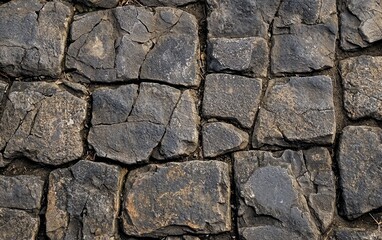 Textured surface of old stone pavement with irregular, weathered edges