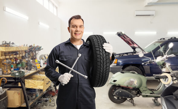 Auto mechanic carrying a tire and holding a wrench tool