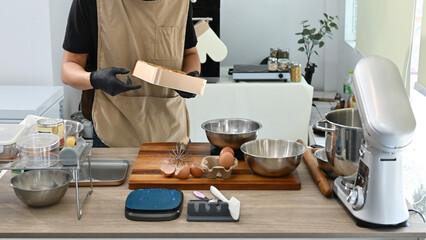 A person is preparing food in a kitchen with a mixer and a bowl of eggs. The kitchen is well-equipped with various utensils and appliances, including a blender.