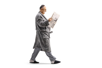 Man in a bathrobe walking and reading a newspaper