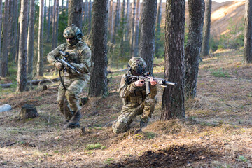 Fototapeta premium Soldiers in the forest. Military men in camouflage with weapons.