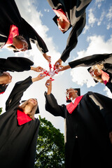 Low ange view vertical photo of groupmates students touch diplomas sunny weather mortarboard gown...