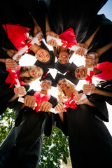Low angle view vertical portrait of group students toothy smile diploma circle mortarboard gown...