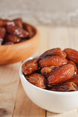 Dates Fruit in a Ceramic Bowl on a Wooden Table..
