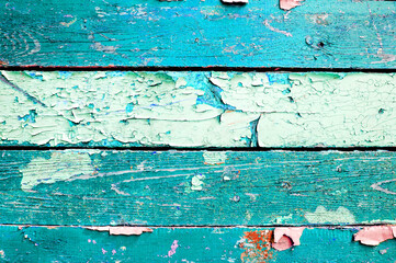 Peeling paint on the wooden surface, closeup of light turquoise peeling paint, wooden planks covered with flaked paint of turquoise color, texture background