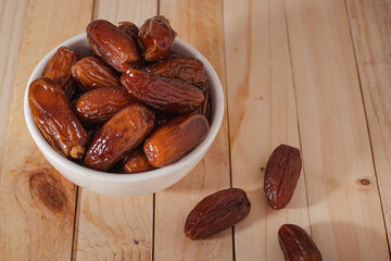 Dates Fruit in a Ceramic Bowl on a Wooden Table..