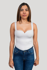 Fototapeta premium Young latin woman posing in white top and jeans on plain background