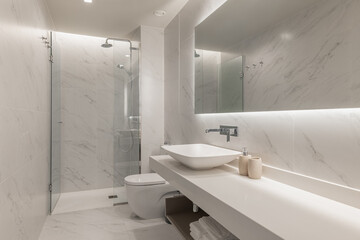 Luxury bathroom with marble-effect walls, modern sink, and backlit mirror for a refined look